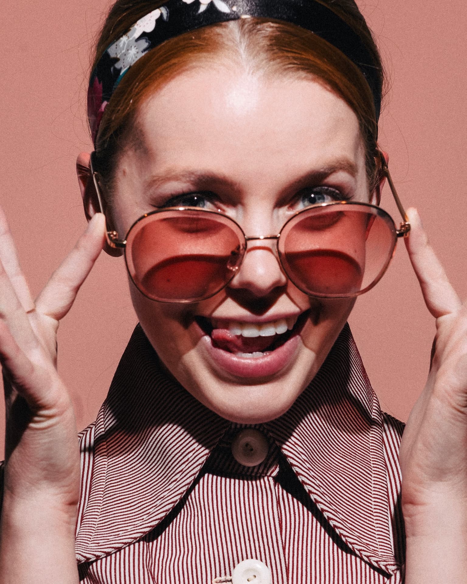 Playful portrait with rose-tinted sunglasses on a pink backdrop by Dan Almasy