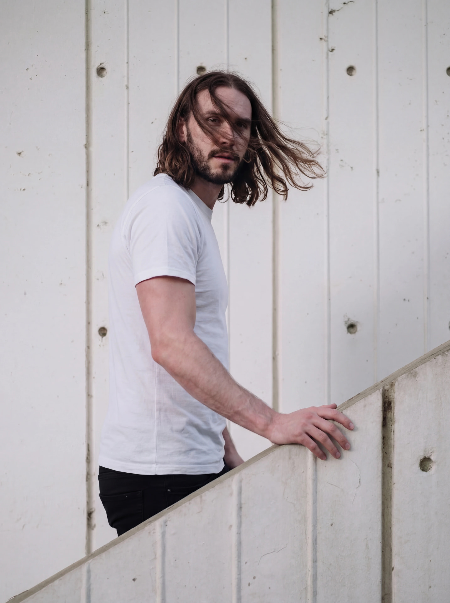 Portrait on a concrete stair against a white wall by Dan Almasy