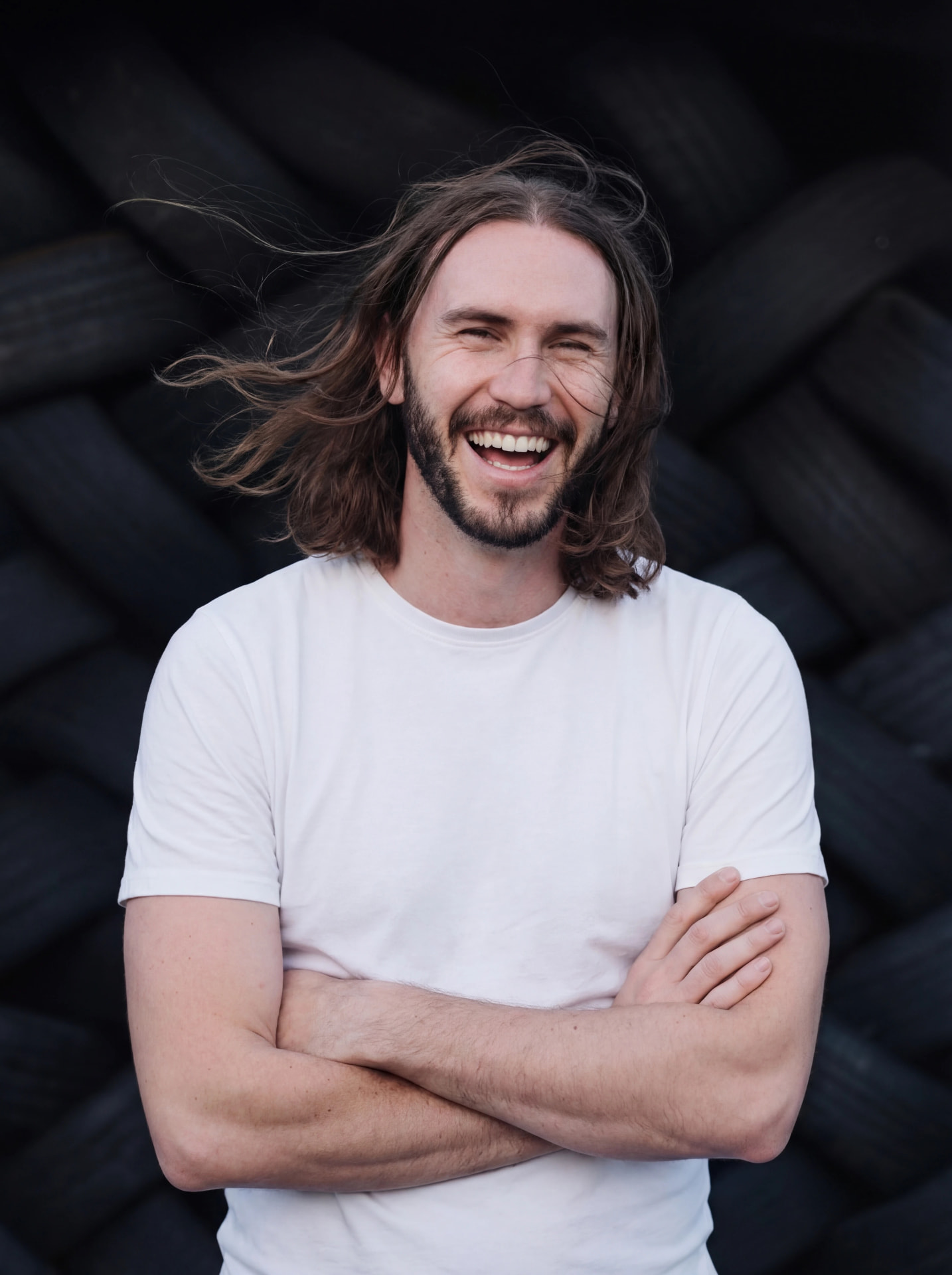 Laughing portrait in a white t-shirt against black timber by Dan Almasy