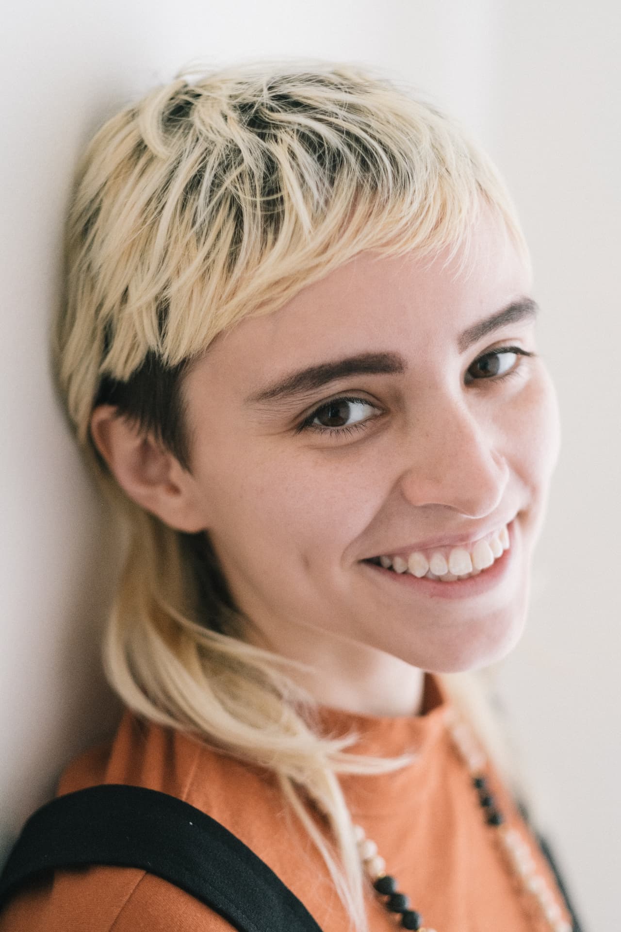 Smiling portrait of a blonde woman in an orange top by Dan Almasy