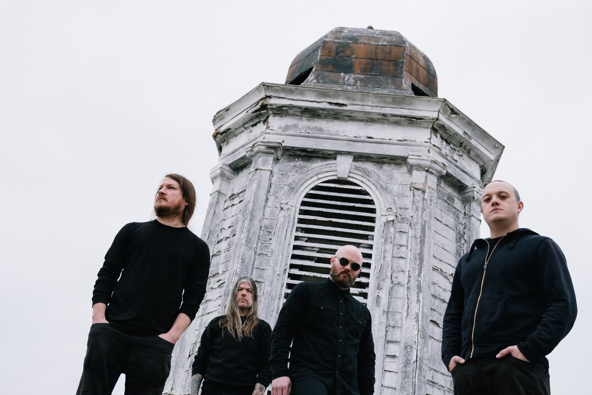 Band photographed from below beneath a weathered white tower by Dan Almasy