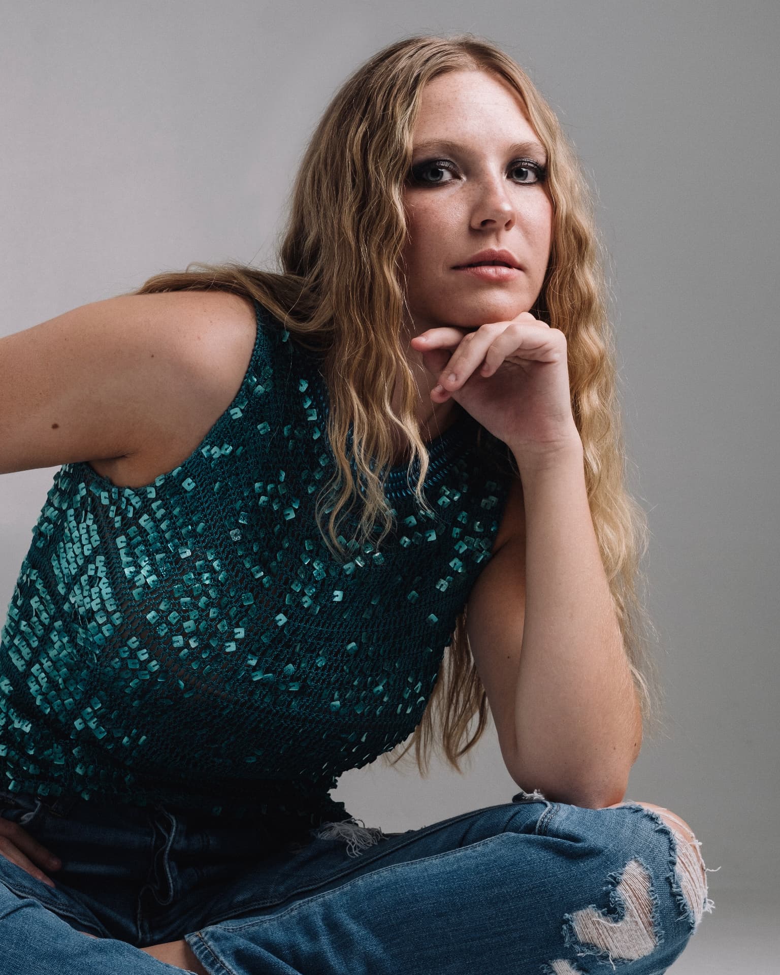 Studio portrait in a teal sequin top against a grey backdrop by Dan Almasy