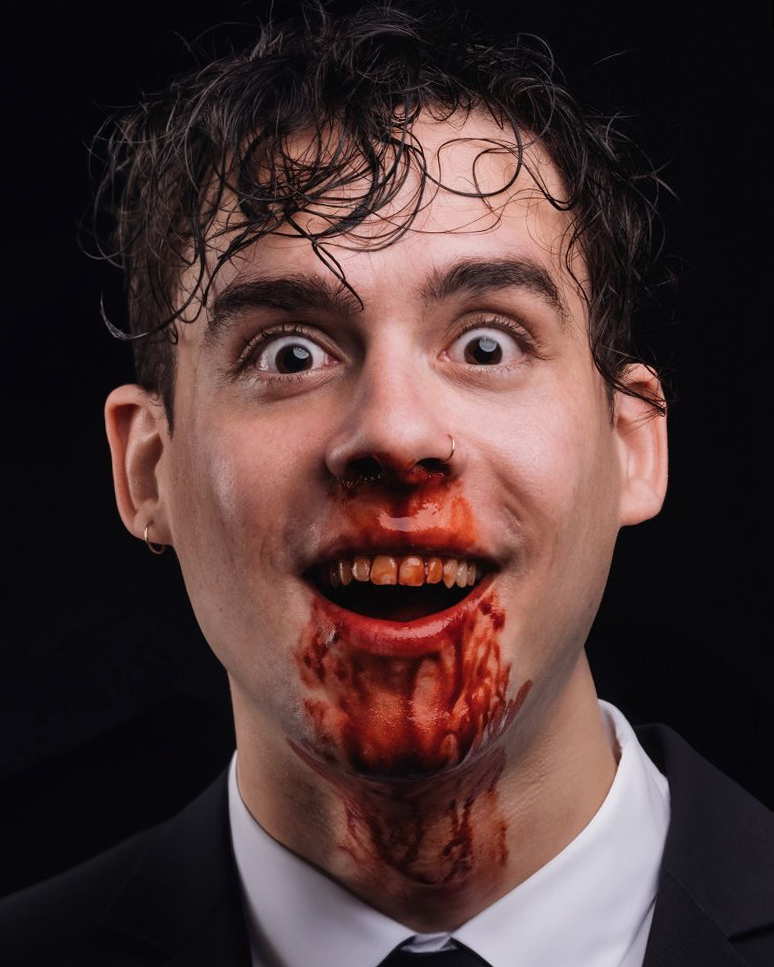 Wide-eyed portrait in a suit with blood at the mouth by Dan Almasy