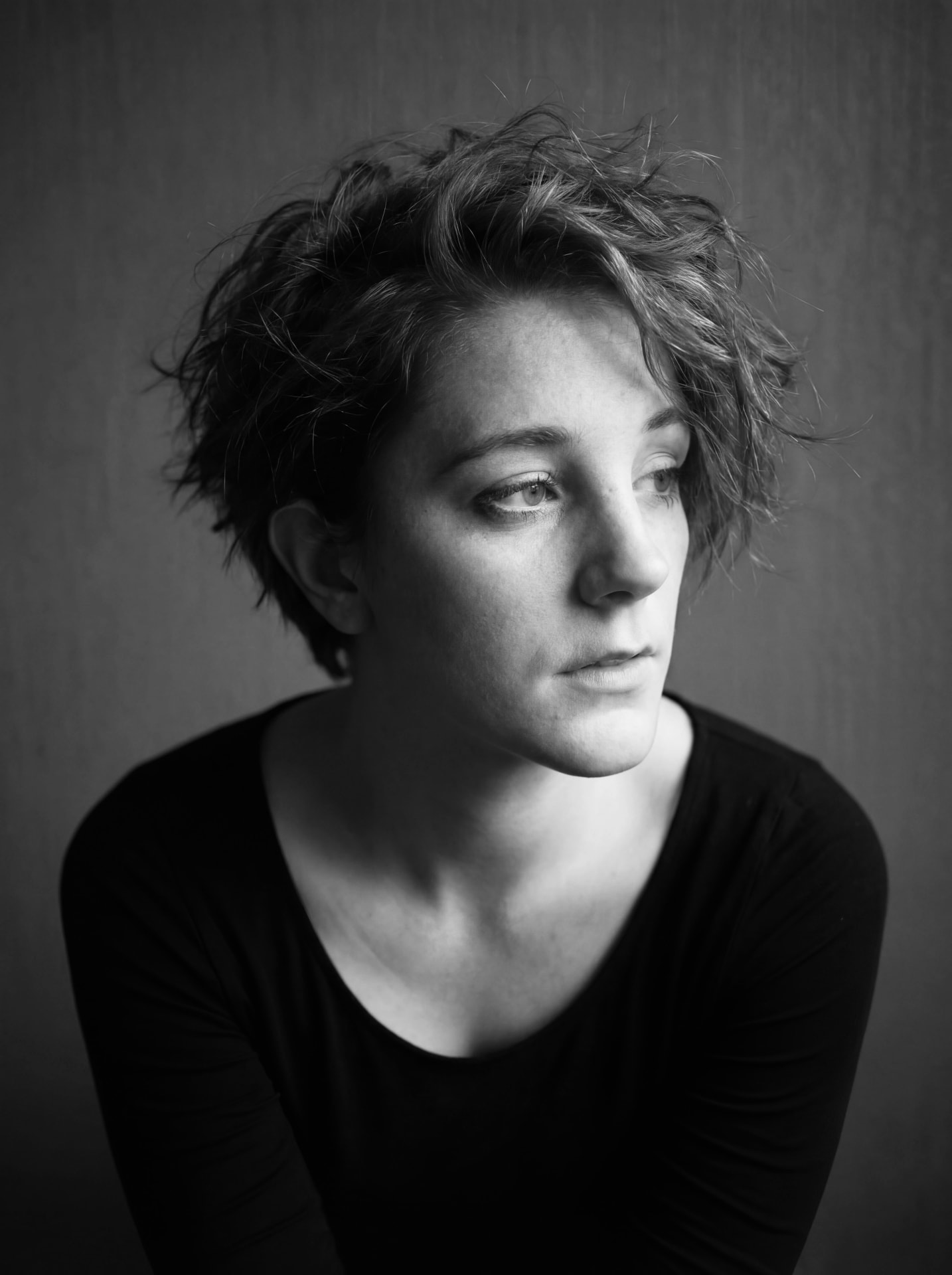 Black and white portrait of a woman with tousled hair looking away by Dan Almasy