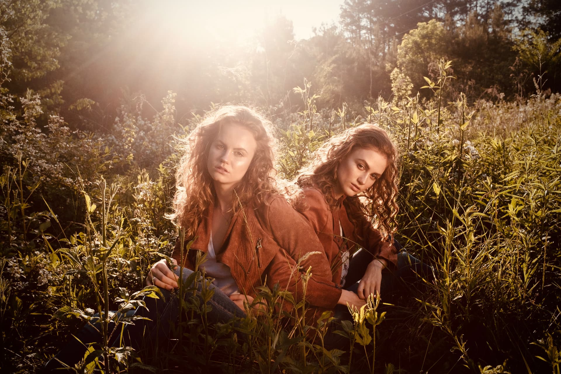 Two models backlit by golden sunlight in a summer field by Dan Almasy