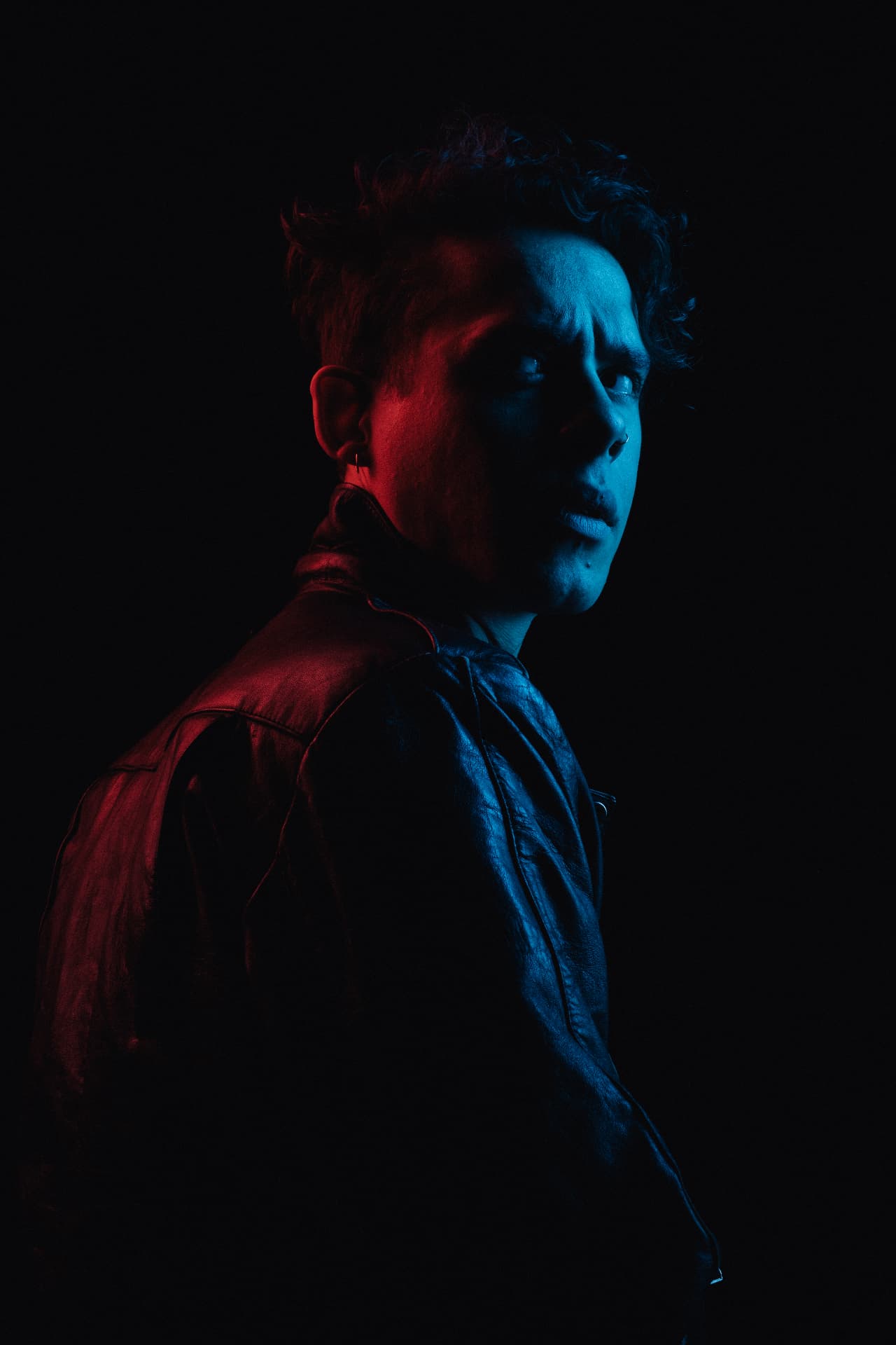 Red and blue split-lit profile portrait in a leather jacket by Dan Almasy