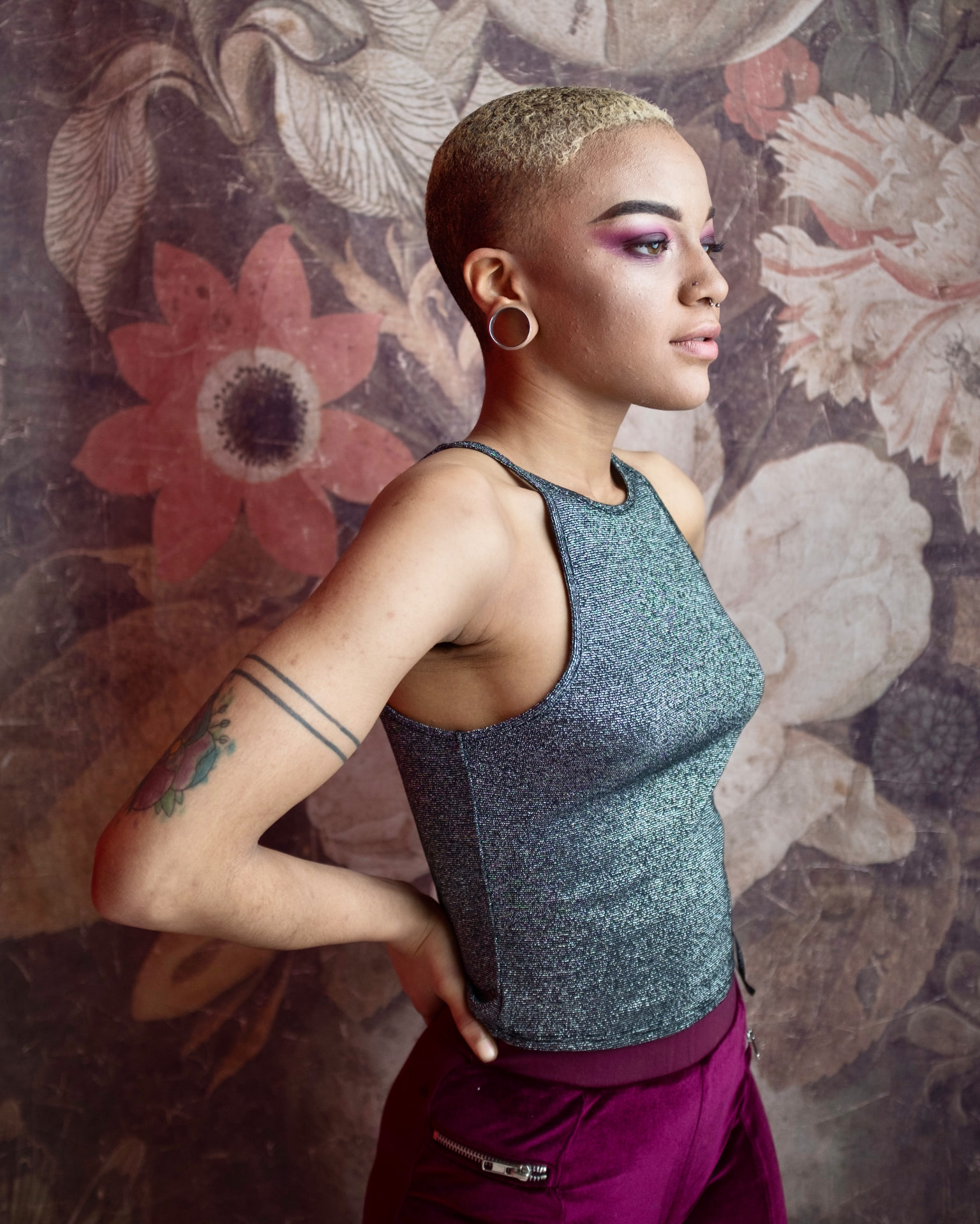 Profile portrait with purple eye makeup against a floral backdrop by Dan Almasy