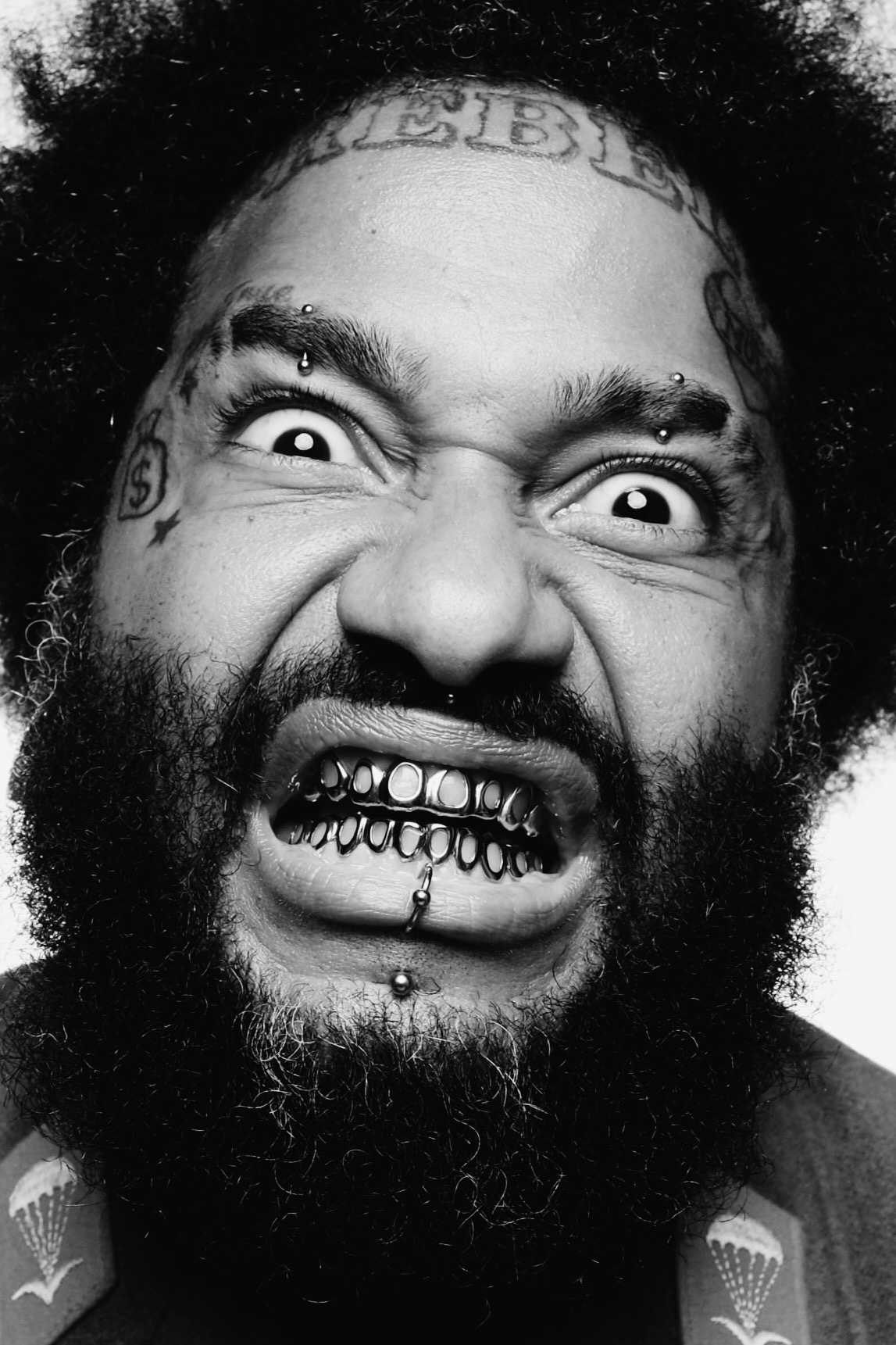 High-contrast black and white portrait with grill and face tattoos by Dan Almasy