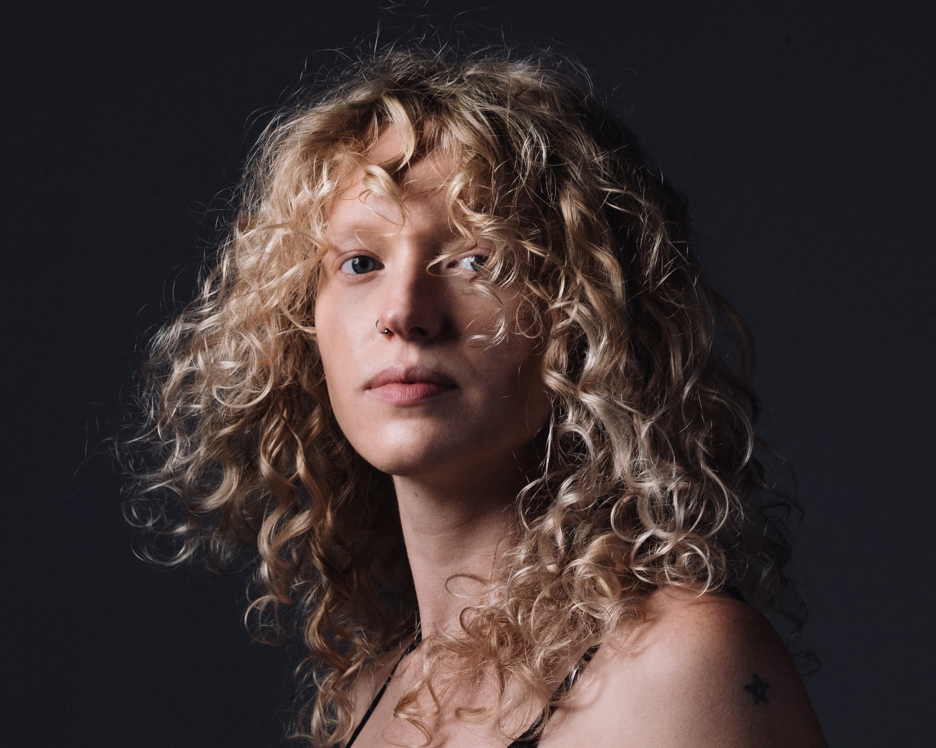 Curly blonde studio portrait on charcoal by Dan Almasy