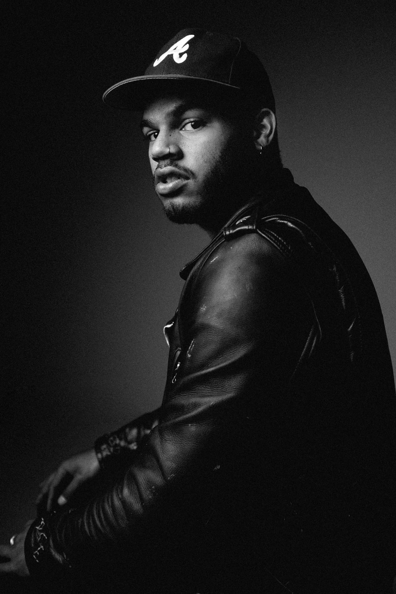 Black and white portrait of a man in a leather jacket and fitted cap by Dan Almasy