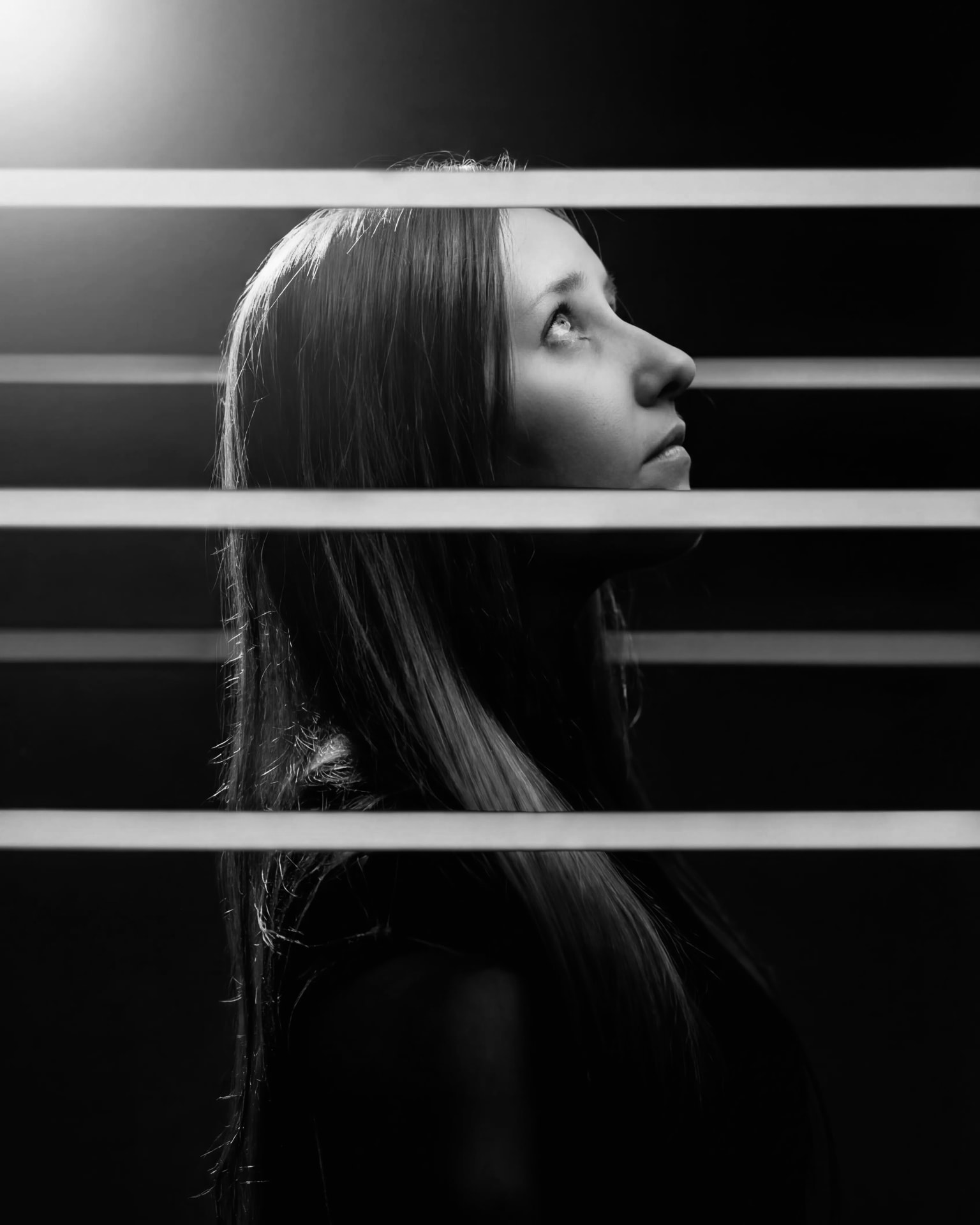 Black and white profile portrait behind horizontal light slats by Dan Almasy